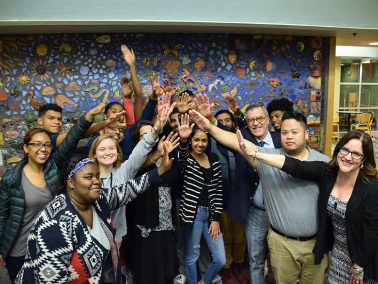 Group of students, faculty and staff from Penn State Abington raising their hands together.